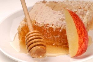 A honeycomb and honey wand on a white plate